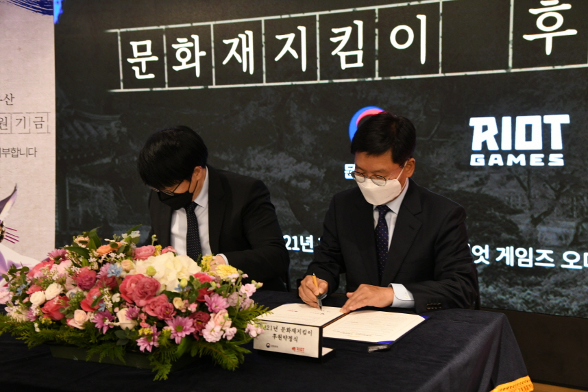 문화재청장과 라이엇게임즈 한국대표가 문화재지킴이 후원 약정서에 서명하는 모습